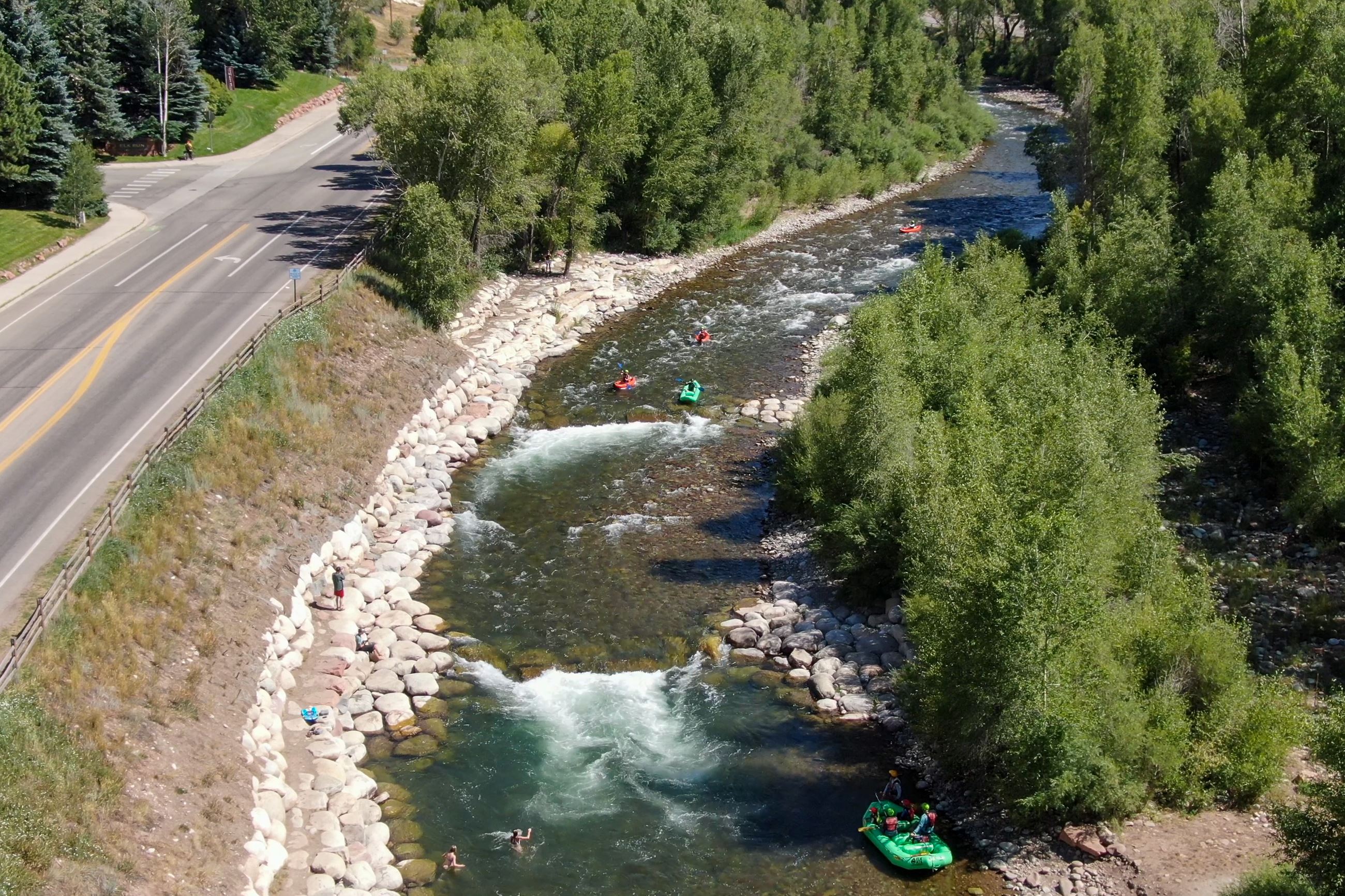 Kayaks float down the Roaring Fork River.